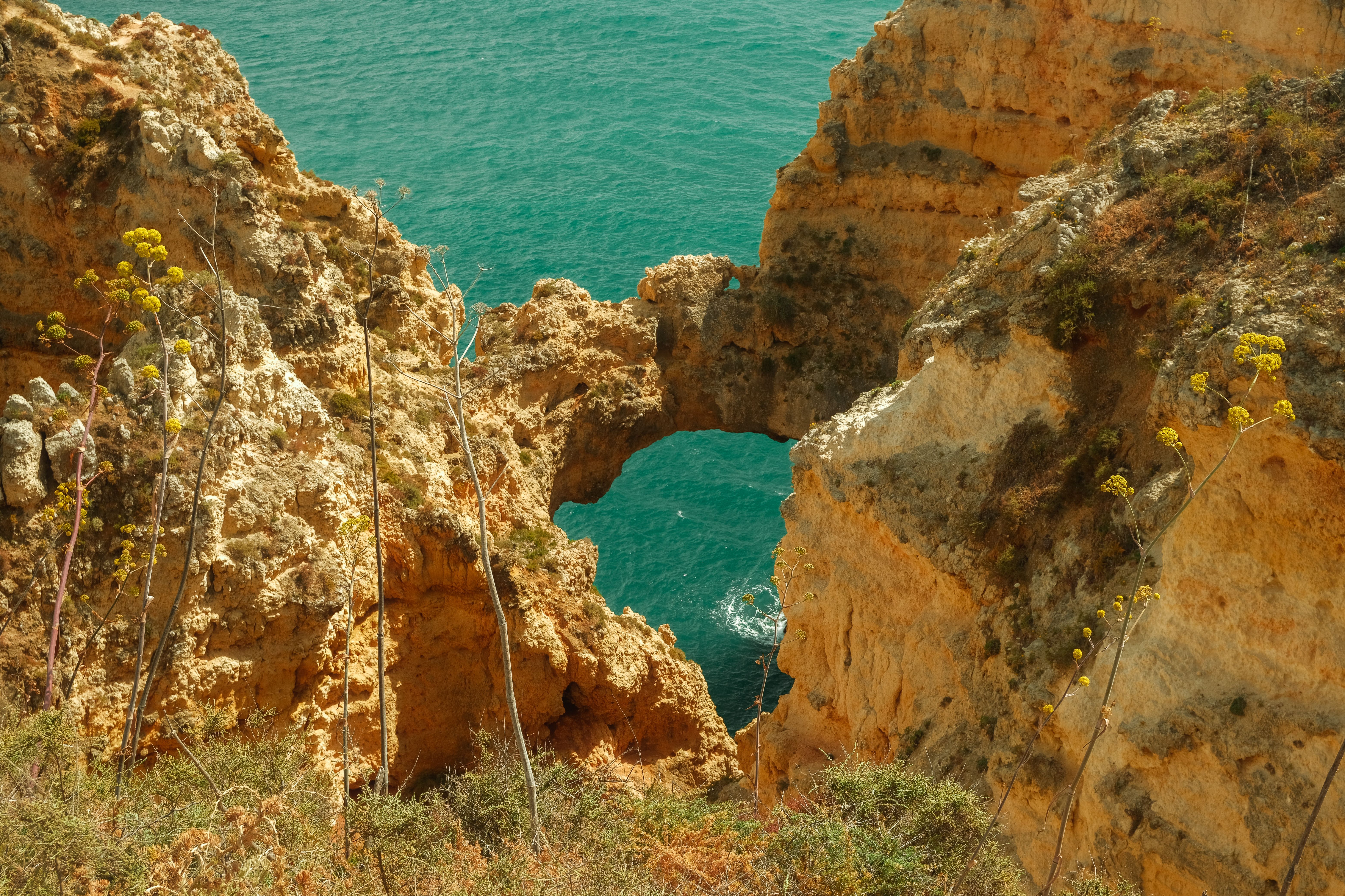 Natural arch between golden cliffs over turquoise water at Ponta da Piedade in Lagos.
