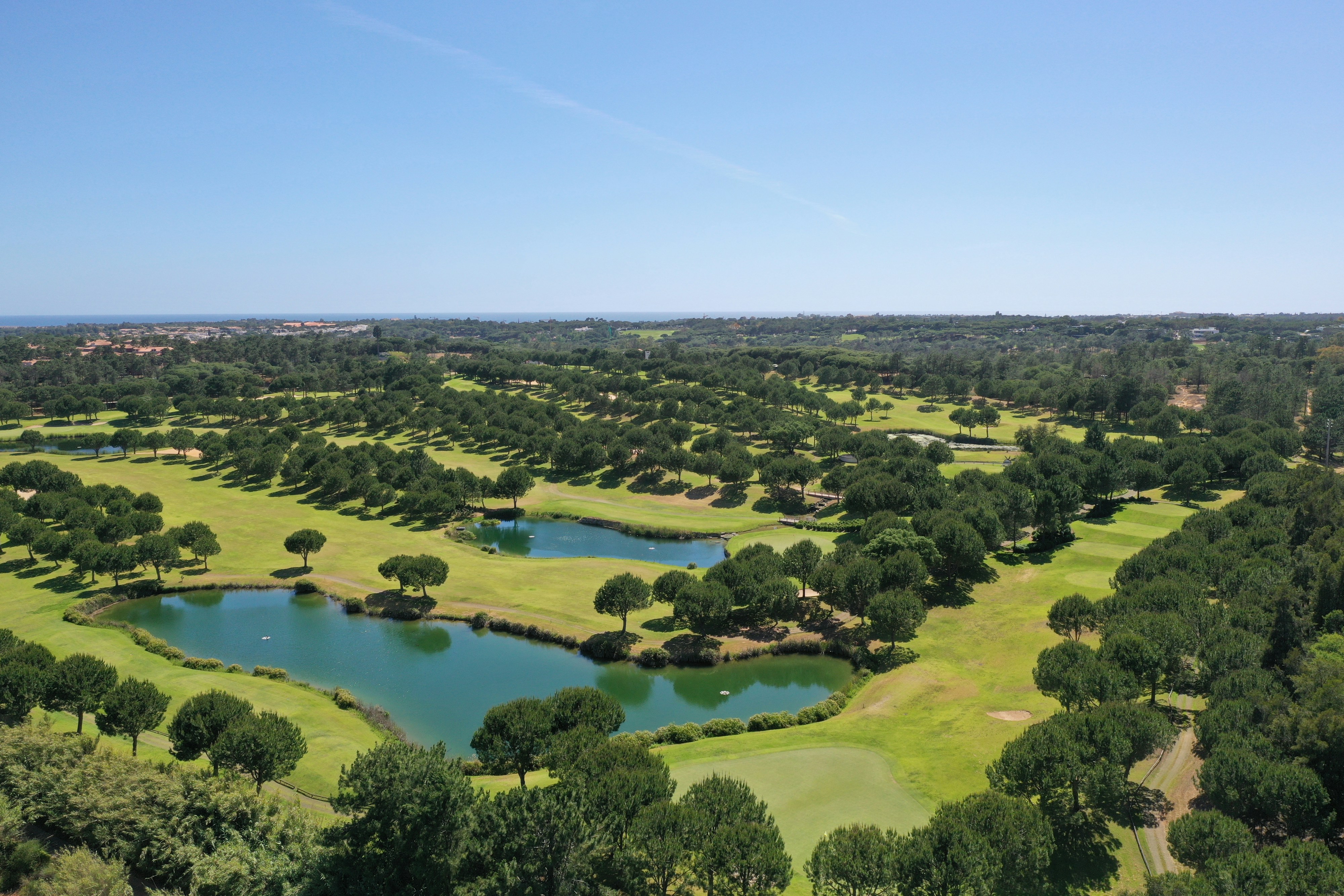 Green golf course with lakes and pine trees in Quinta do Lago.
