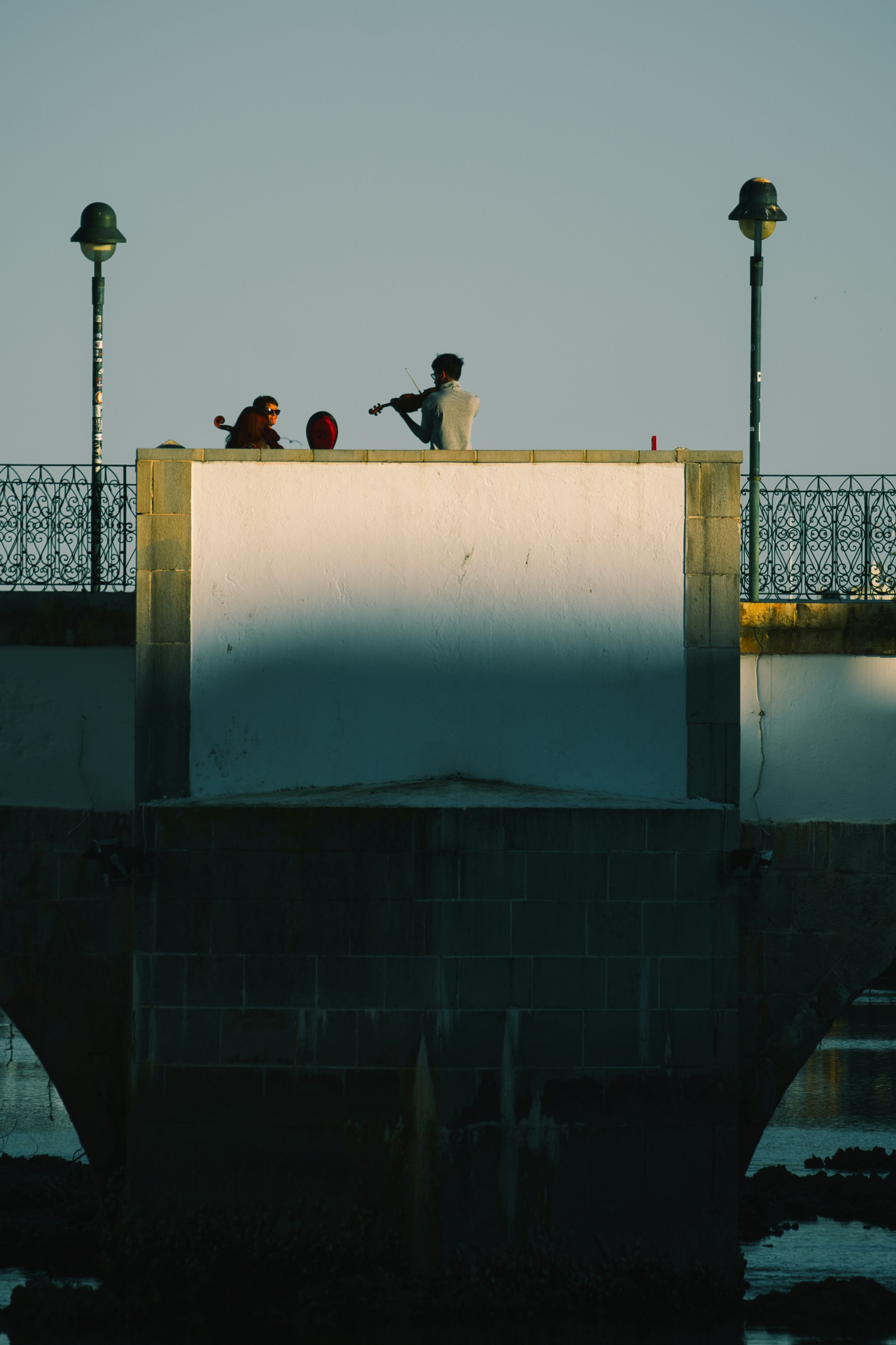 Musicians on a historic bridge beside the river in Tavira.