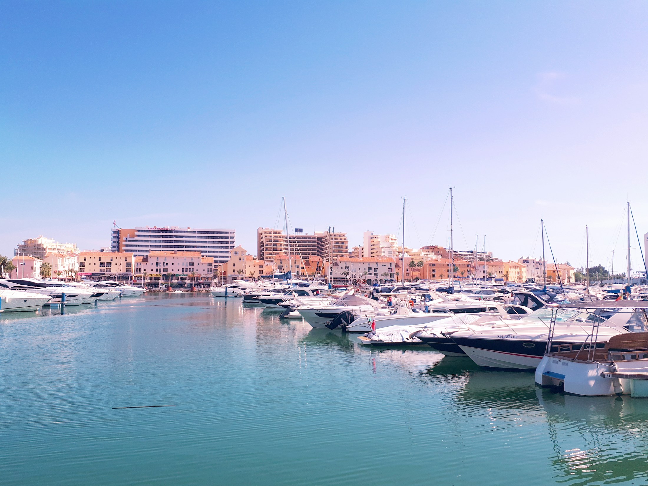 Boats moored at Vilamoura Marina beneath a blue sky.